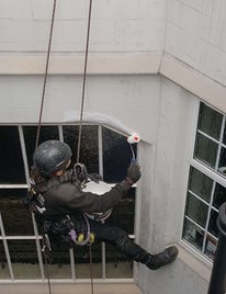 A worker using rope access methods to reach challenging areas of a building,