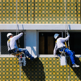 men abseiling and painting a building 