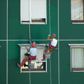 abseiler painting a bright green wall