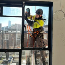 A rope access technician doing glazing work in London